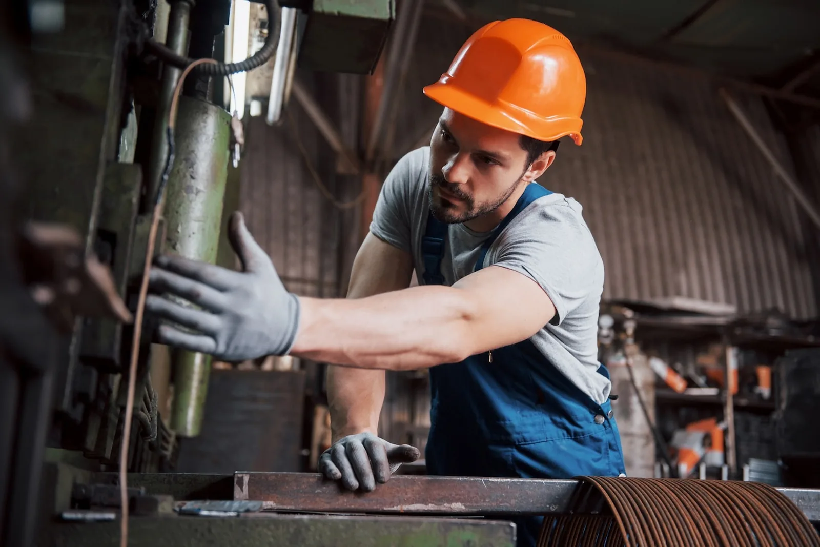 Industrial worker in a safety helmet and protective gloves operating machinery
